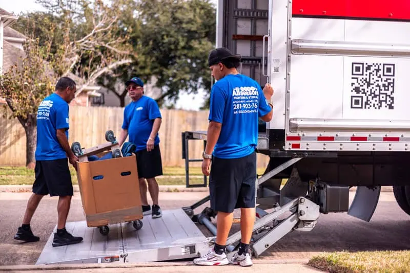Local movers unloading boxes from a truck liftgate in Sugar Land