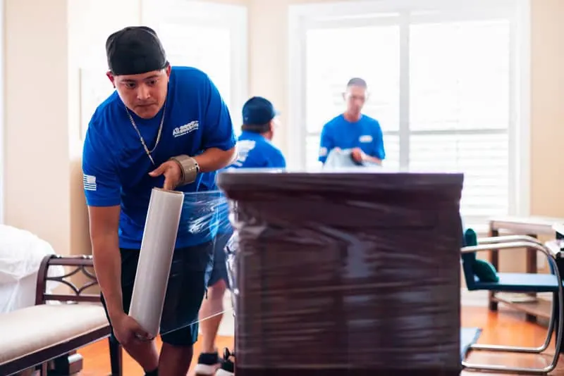 Mover stretch wrapping a dresser in a Sugar Land bedroom