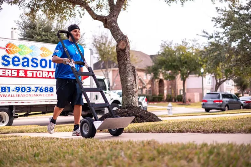 Mover pushing a hand truck across a lawn in Sugar Land, TX