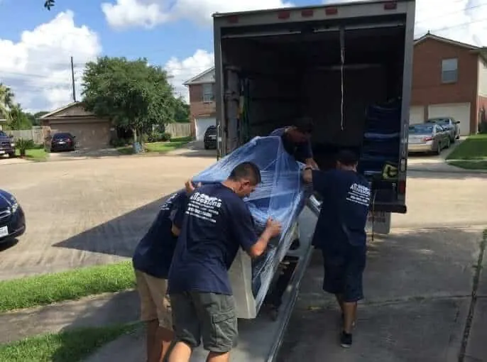 Movers loading a wrapped item into the truck in Sugar Land, TX