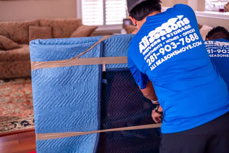 Movers padding furniture with moving blankets in Sugar Land