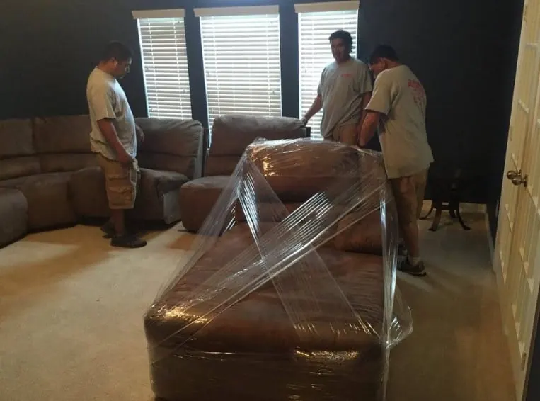Movers wrapping a sofa during a home move in Sugar Land