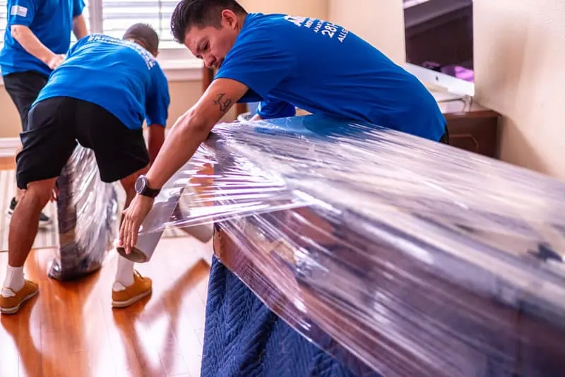 Movers wrapping a table in plastic in Sugar Land, TX