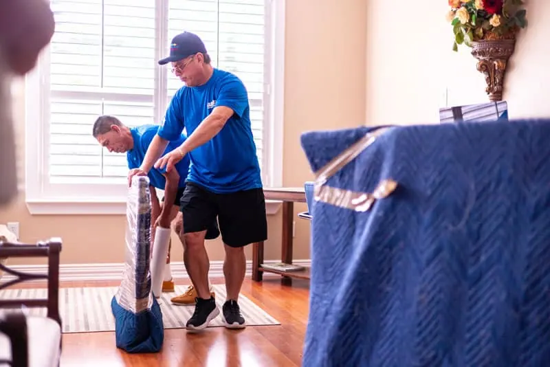 Movers wrapping furniture inside a Sugar Land home