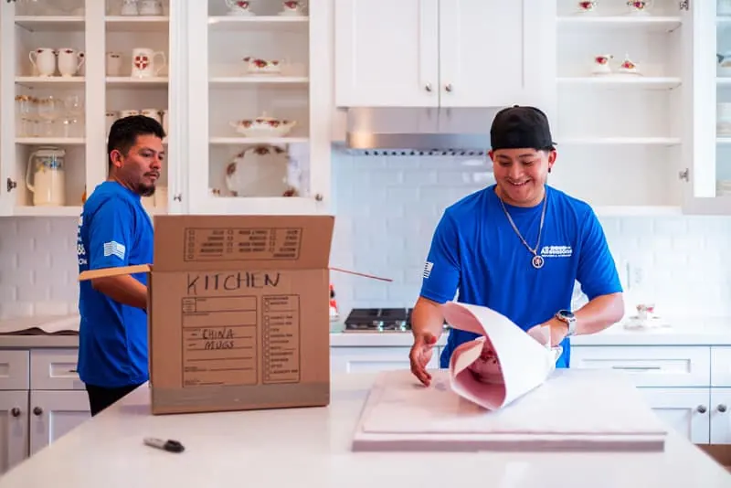 Mover packing kitchen items into a labeled box in Sugar Land